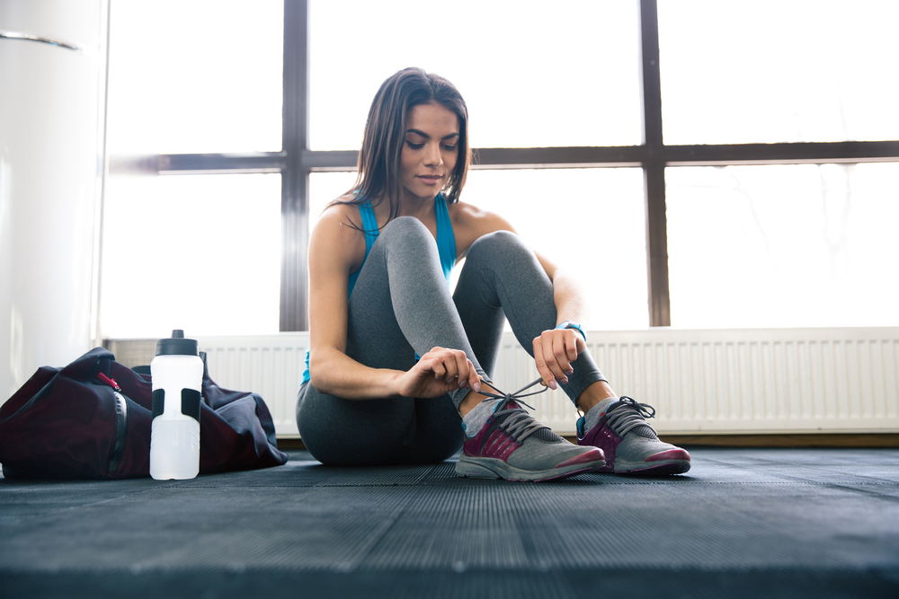 Beautiful woman tying shoelaces at gym